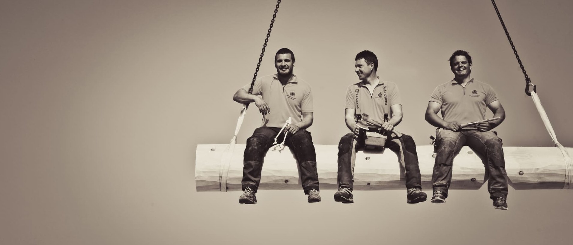 Männer sitzend auf einem hängenden Naturstamm in der Luft