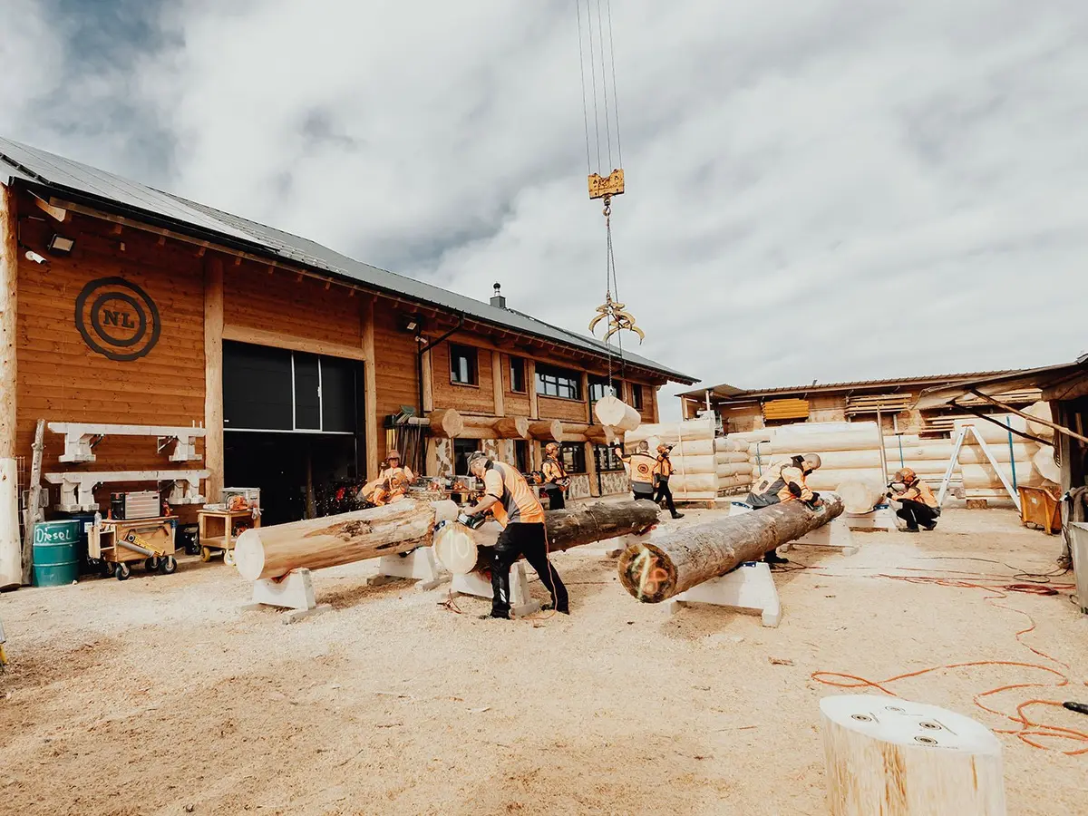 Mitarbeiter beim Bearbeiten der Holzstämme für den Blockhausbau
